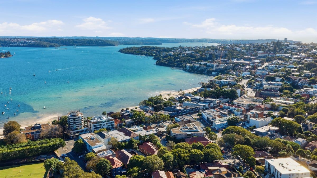 Stunning aerial view of Sydney Harbor with cityscape and ocean in daylight.