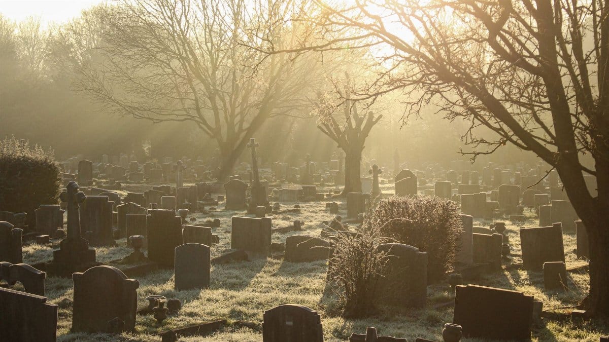 Sunrise over a tranquil cemetery with frosted gravestones.
