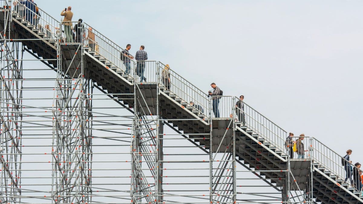 People climbing a large scaffolding structure outdoors, showcasing urban architecture.