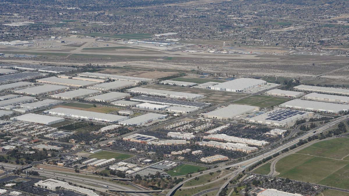 Expansive aerial shot of industrial area near a major airport and urban landscape.