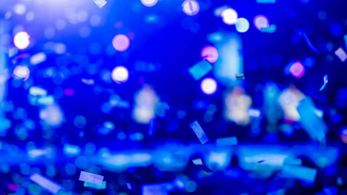 A dynamic shot of colorful confetti and blue bokeh lights, capturing a festive atmosphere.
