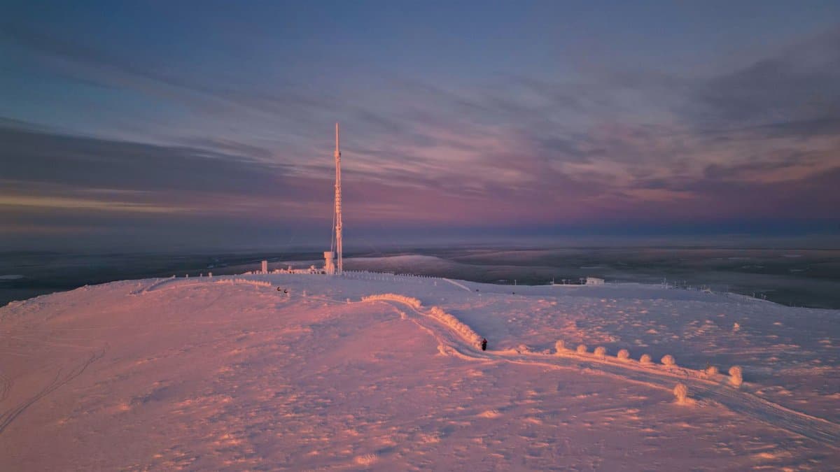 A captivating snowy landscape with a telecommunications tower at sunset in Ylläsjärvi, Finland.