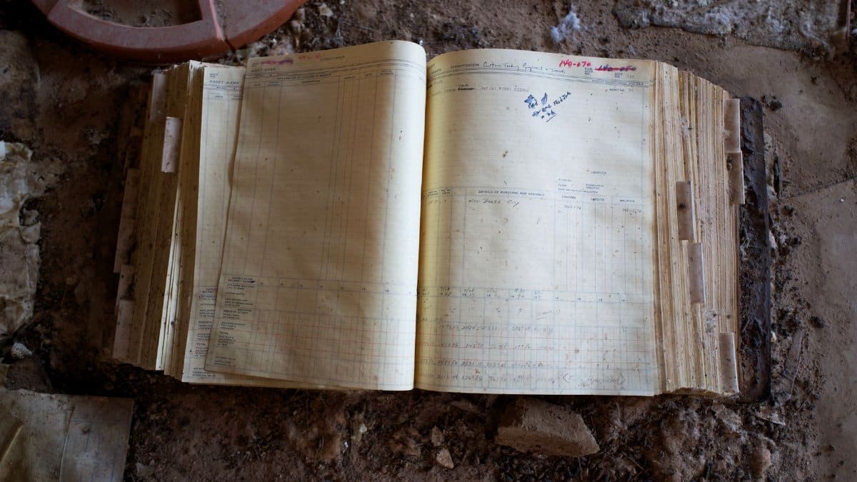 An open ledger book on a dusty floor, evoking a sense of history and abandonment.