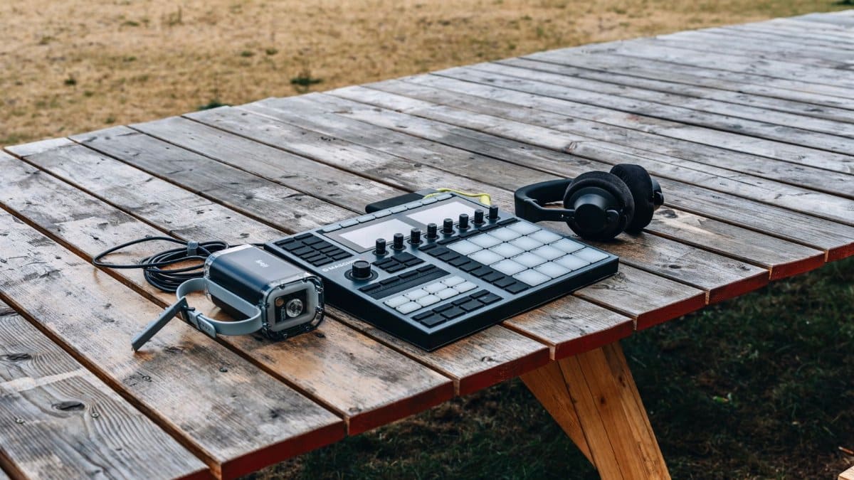 Outdoor setup of beat-making equipment and headphones on a rustic wooden table.