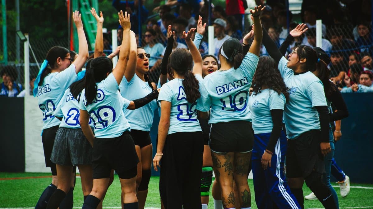 A women's soccer team celebrates a win on a vibrant outdoor sports field.