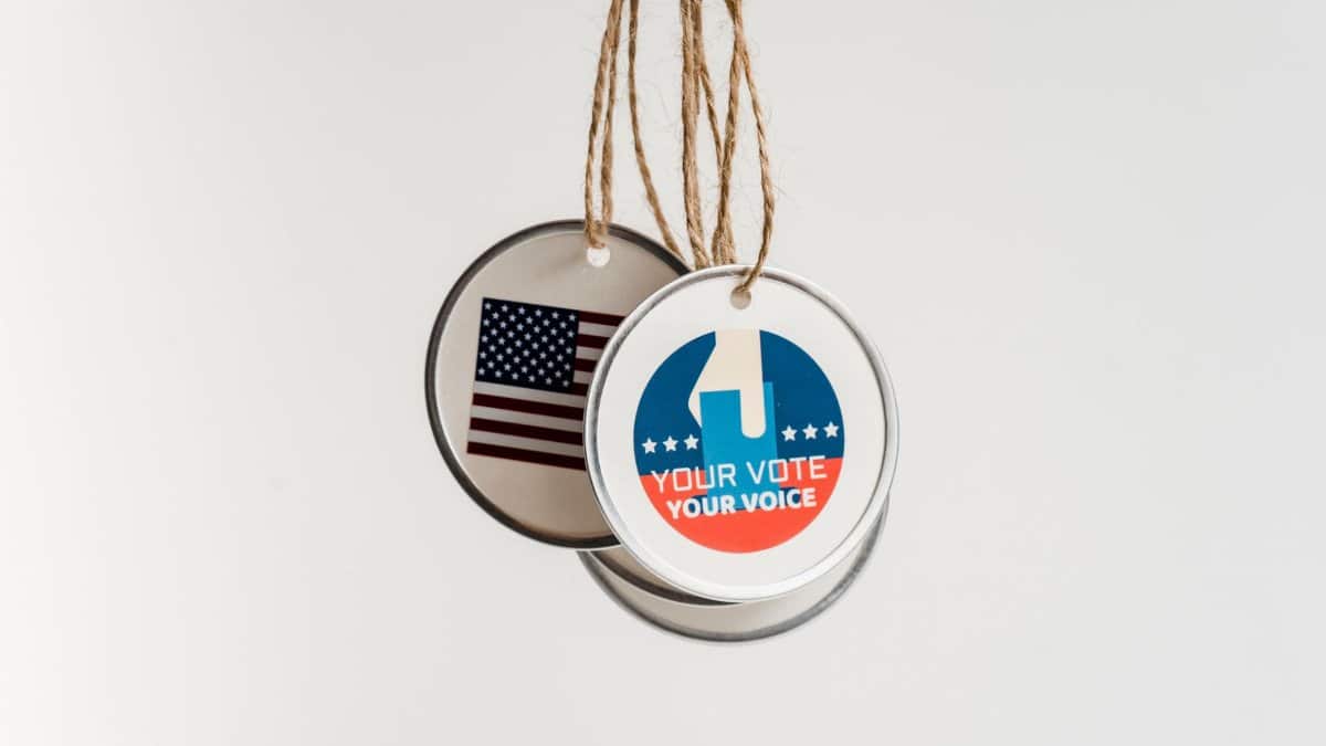 Close-up view of USA voting badges hanging on strings against a white background.