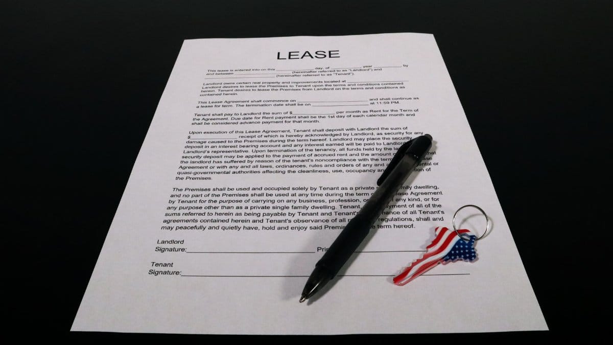 Lease agreement document with pen and American flag keychain on a black table.