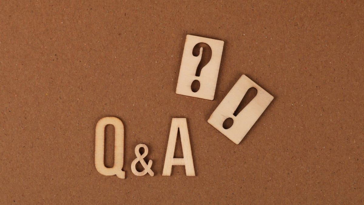 Wooden cutouts of Q&A with question and exclamation marks on a brown backdrop.