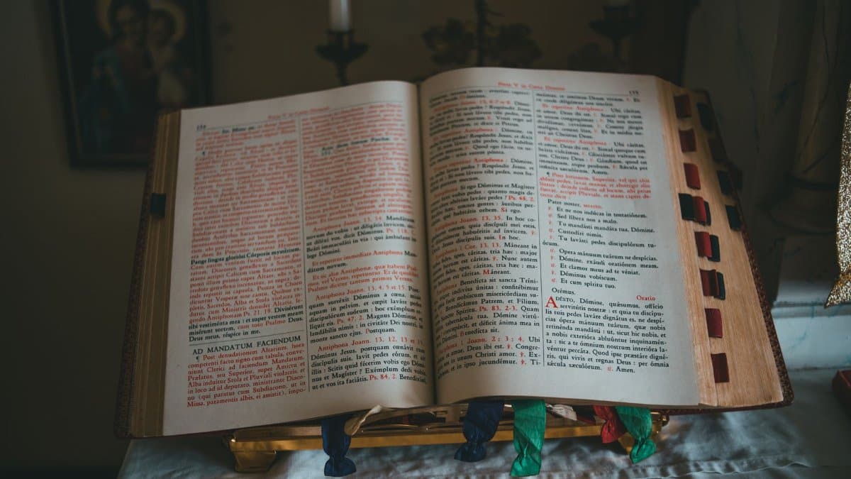 A Bible open on an altar with Latin text, featuring colored ribbons.