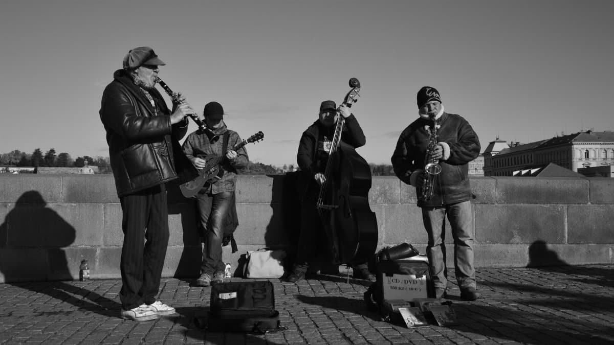 A group of musicians performing with instruments outdoors in a monochrome setting.