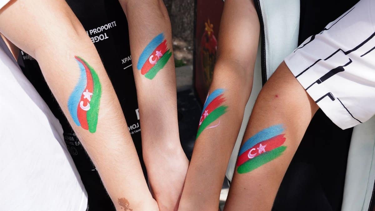 Close-up of arms with Azerbaijani flag painted outdoors symbolizing unity and patriotism.