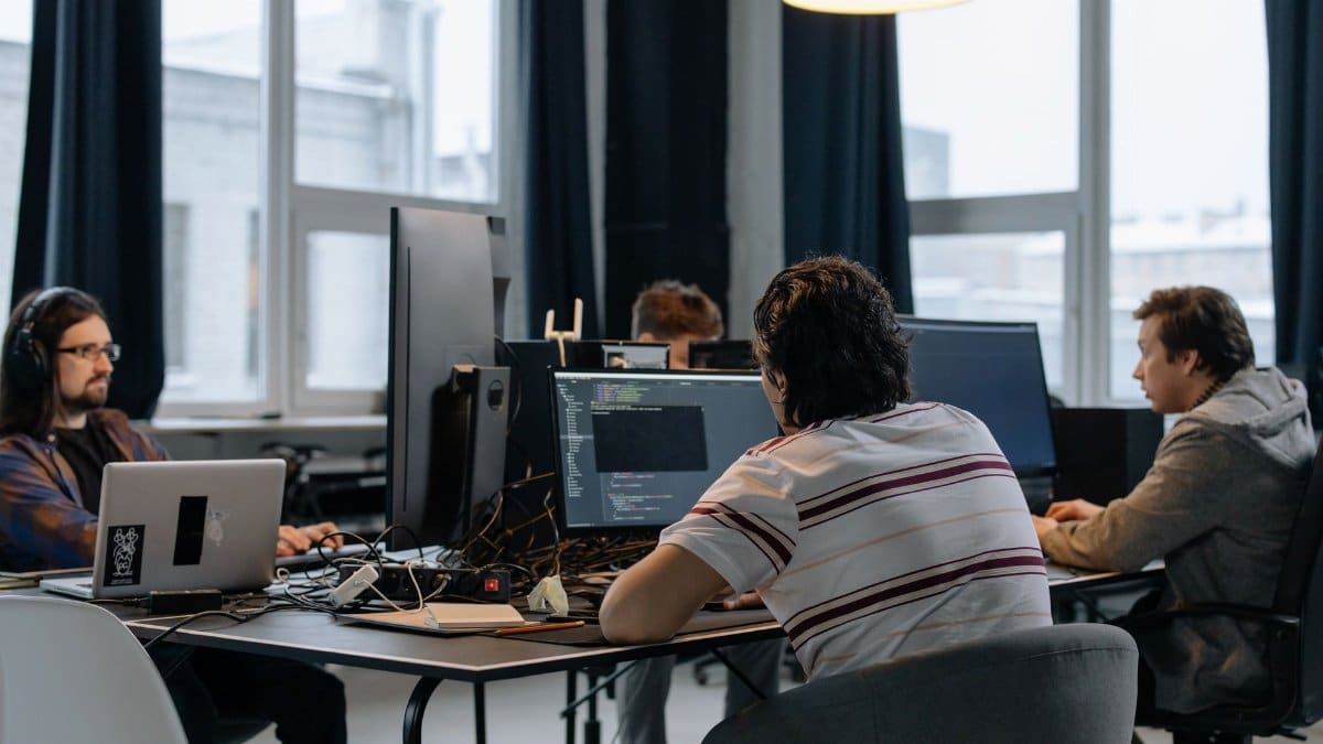 Team of developers working together on computers in a modern tech office.
