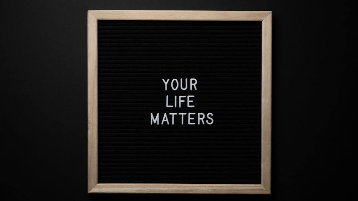 From above composition of black chalkboard with wooden frame with text YOUR LIFE MATTERS on center on black background