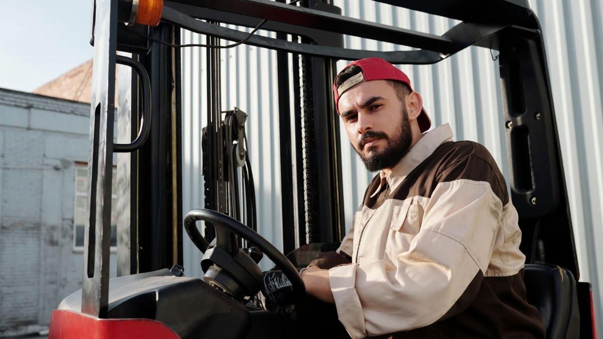 Forklift operator confidently working in an industrial outdoor environment, showcasing focus and skill.