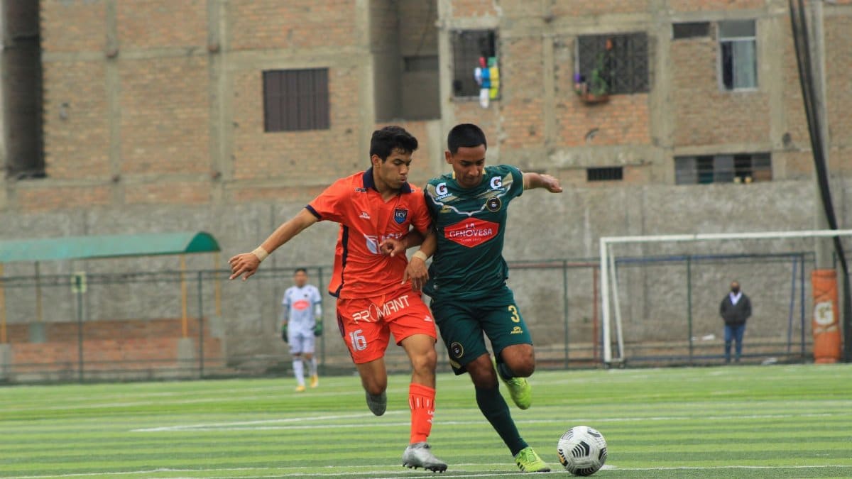 Two soccer players challenging for the ball during a match on an urban field.