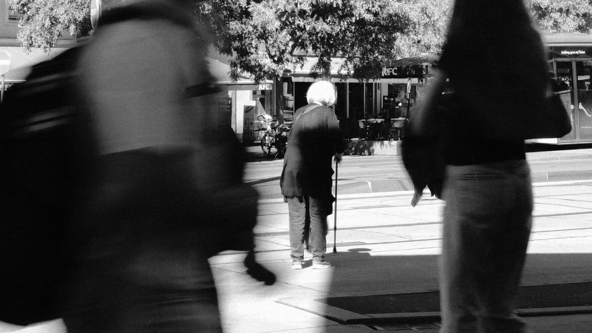 Black and white street photo capturing urban life with motion blur.