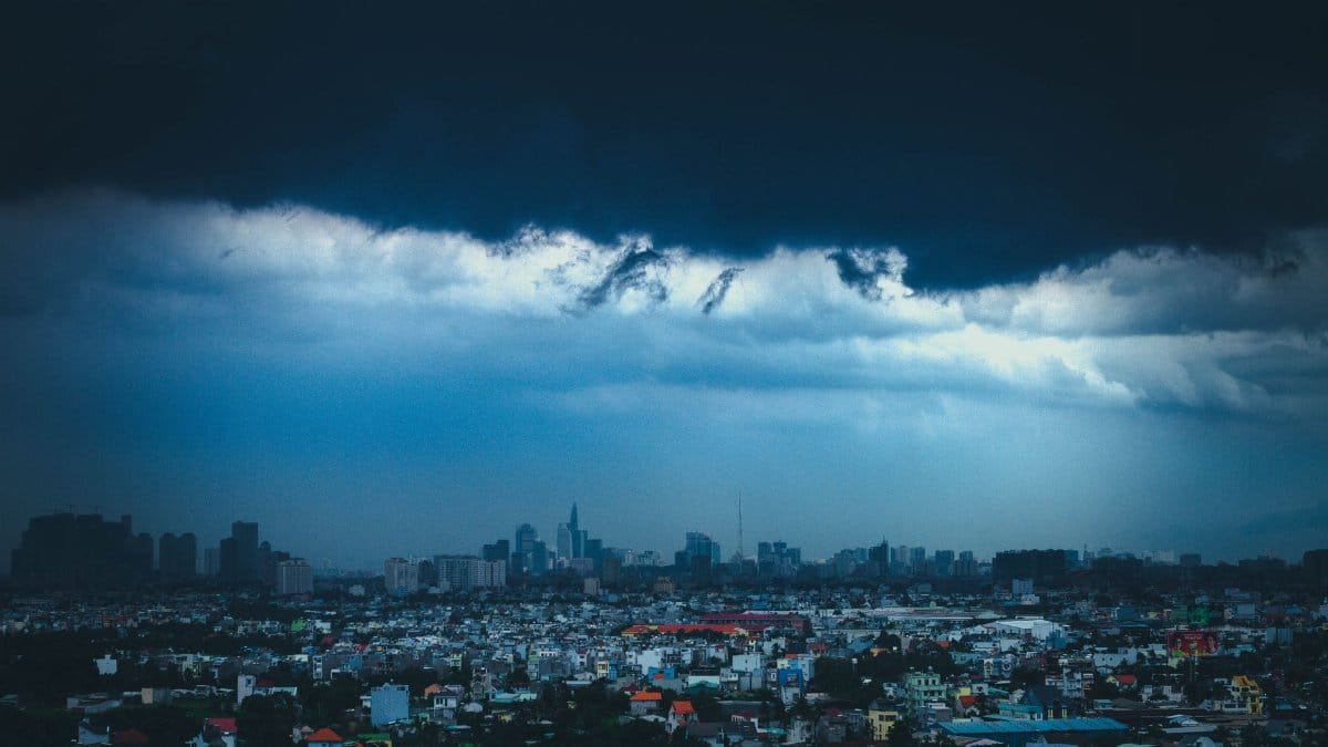Dark storm clouds loom over the vibrant skyline of Ho Chi Minh City, Vietnam, creating a dramatic urban landscape.