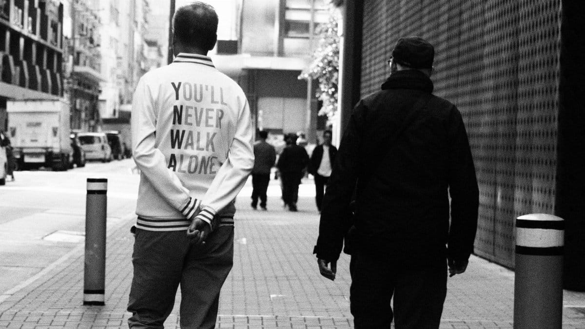 A candid street photo in Hong Kong with two people walking and urban architecture.