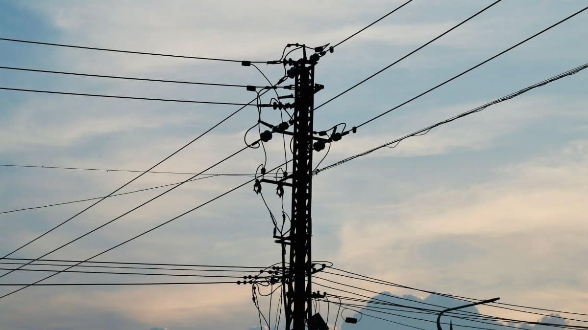 Silhouette of power lines and pole against a vibrant sunset sky.