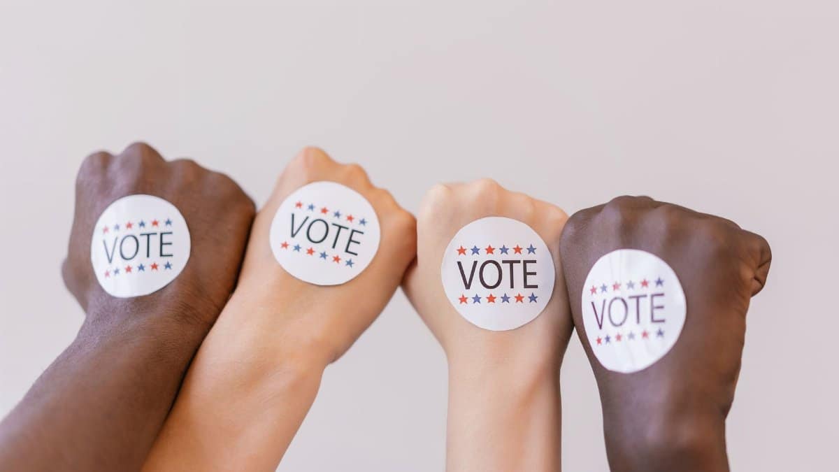 Close-up of diverse hands showing unity with vote stickers emphasizing democracy.