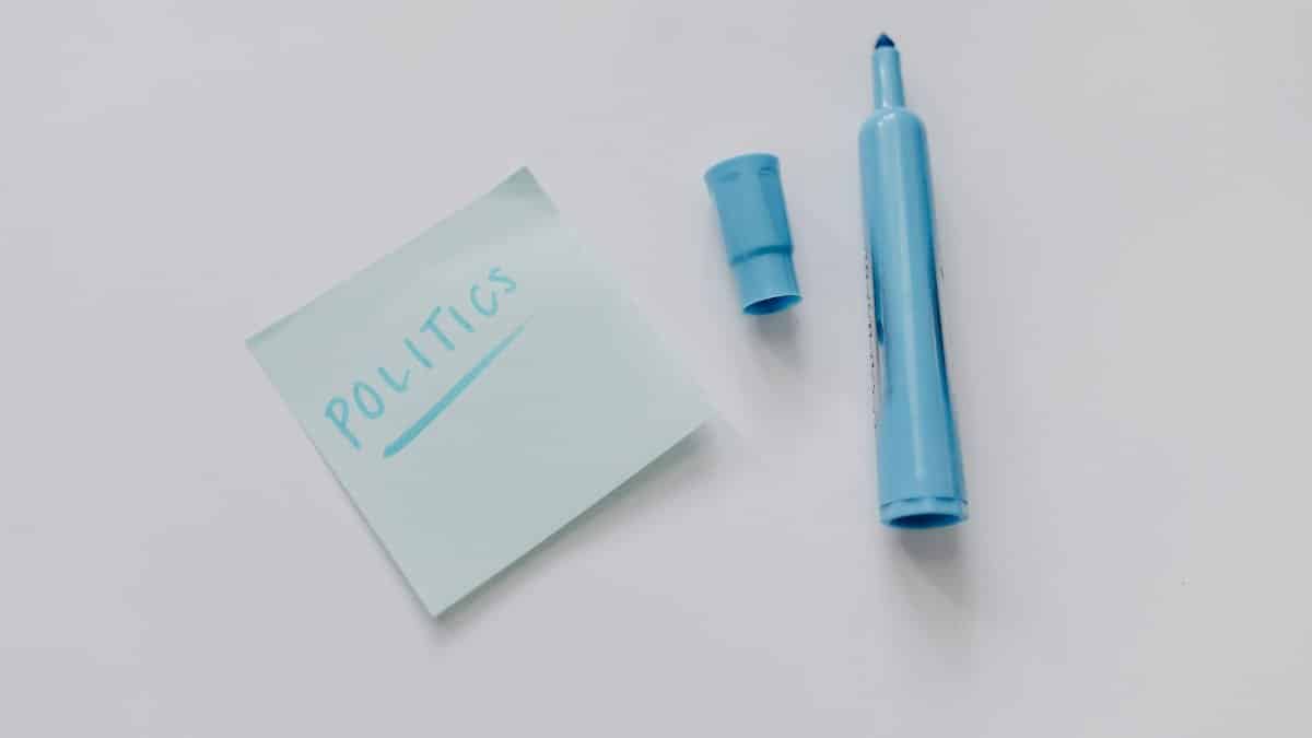 A blue marker and a note reading 'politics' on a white surface, top view.