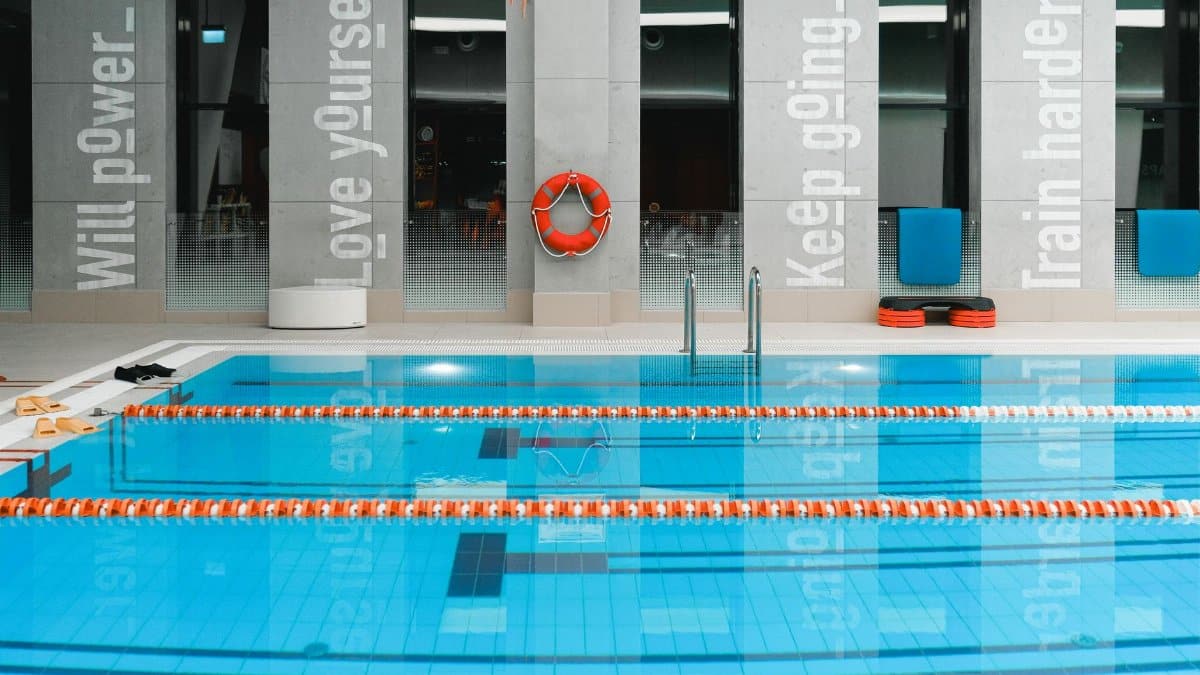 A modern indoor swimming pool with motivational quotes on the walls and clear water.