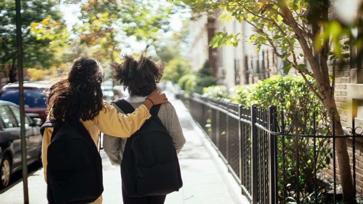 Back view of unrecognizable girls walking together along street while returning home from school