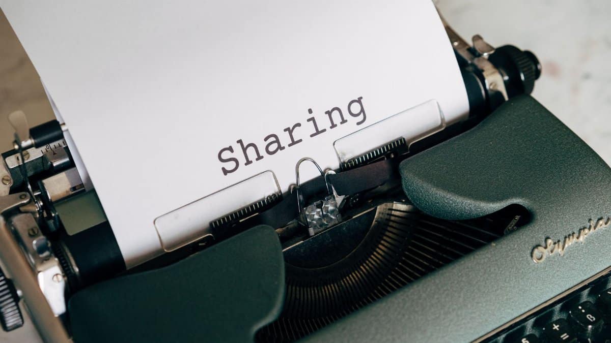 Close-up of a vintage typewriter with paper showing the word 'Sharing', conveying retro communication.