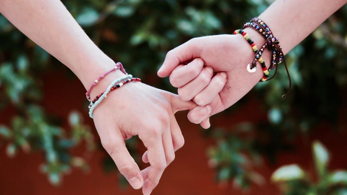 Two hands with colorful bracelets interlocked, symbolizing friendship and connection.