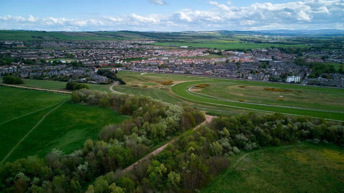 Scenic aerial view of East Lothian countryside in Scotland, showcasing lush green landscapes and a vibrant town.