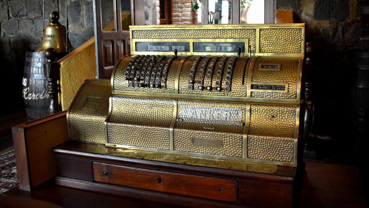 A beautifully preserved vintage brass cash register displayed in a rustic, wooden interior.