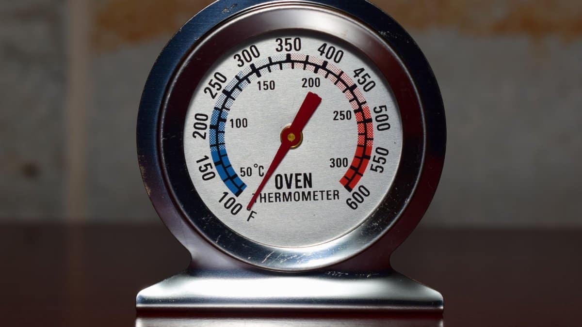 Close-up of a metallic oven thermometer showing temperature in Celsius and Fahrenheit.