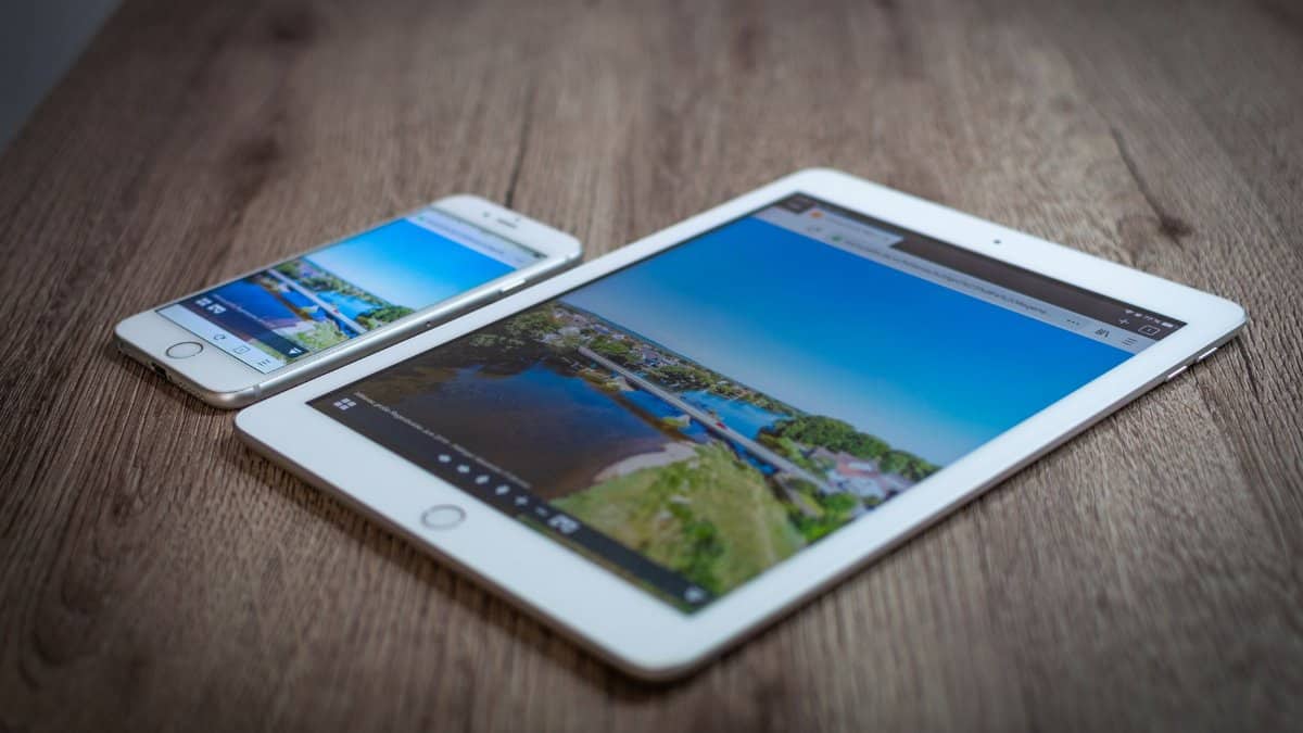 iPad and iPhone showing a scenic landscape on a wooden table, highlighting portability and technology.