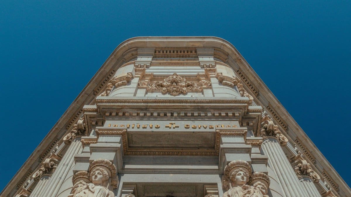 Ornate architecture of Instituto Cervantes with sculptures, set against a clear blue sky.