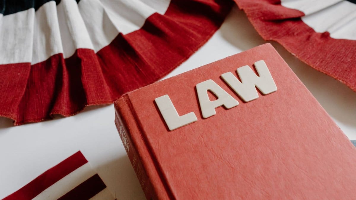 A law book with bold letters placed beside a red, white, and black decorative ribbon.