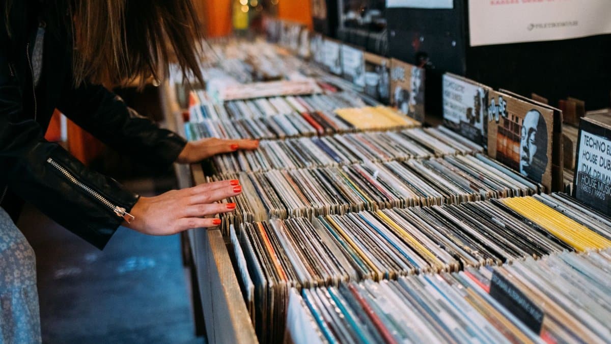 Woman browsing vinyl records in a cozy vintage music store, enjoying leisure time.