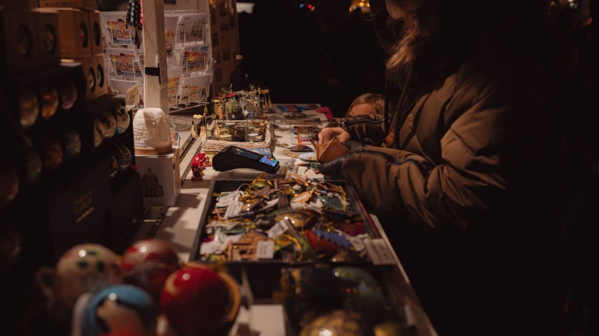 Warm and inviting evening market stall scene with people browsing souvenirs and handmade crafts.