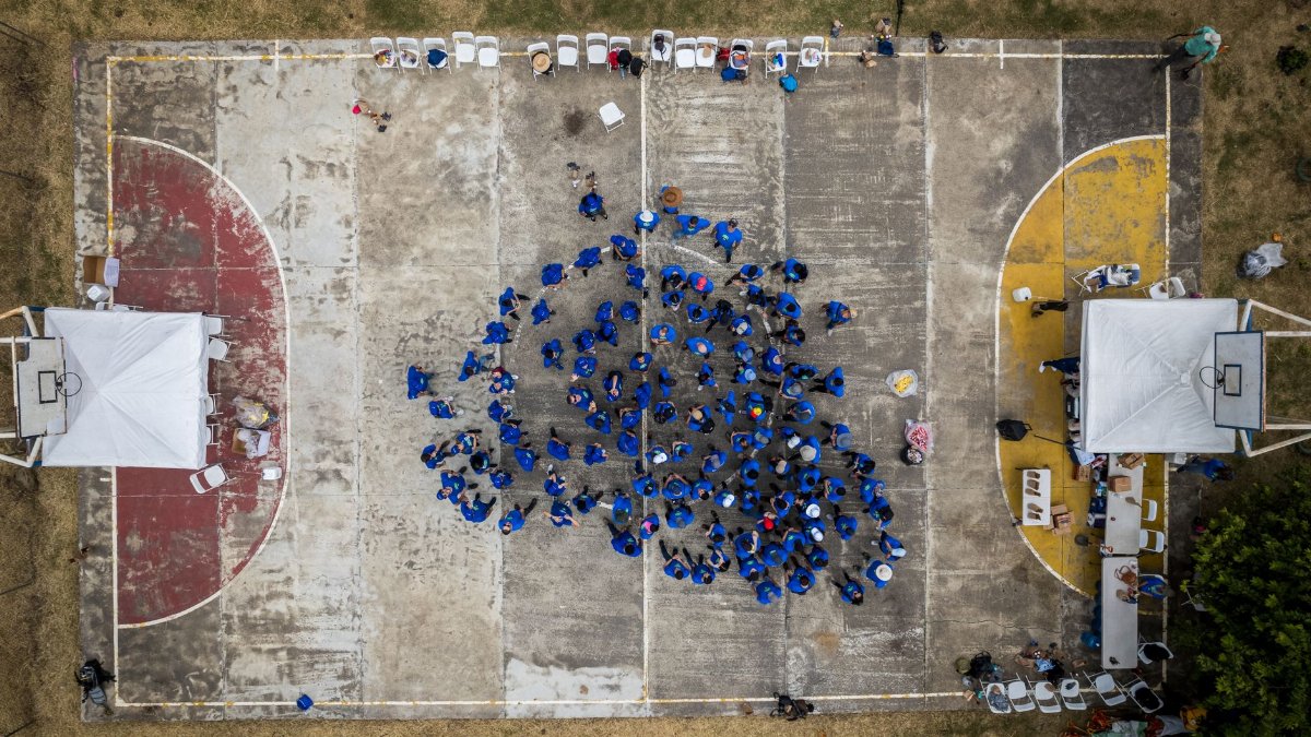 Drone shot of people in blue clothes on an outdoor basketball court in San José, Costa Rica.
