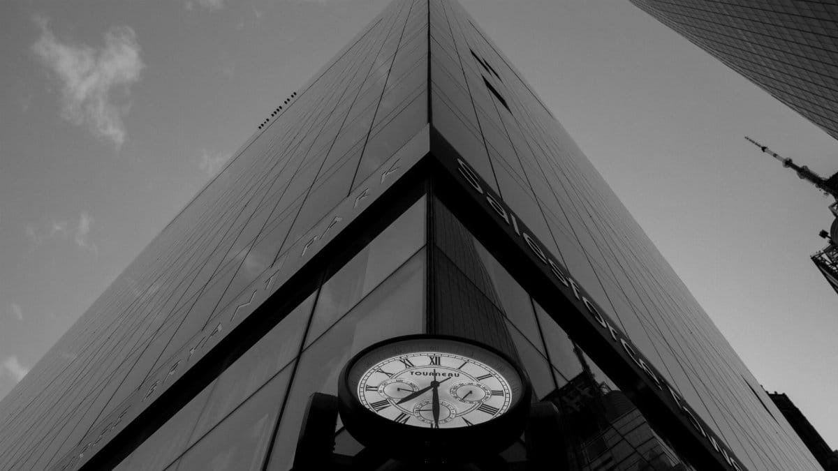 Black and white image of a skyscraper with a clock at its base in New York City.