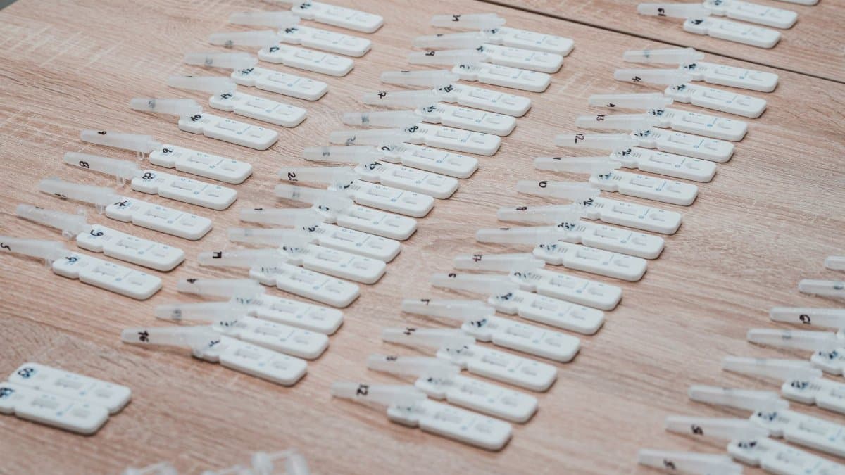Multiple COVID-19 test kits displayed neatly on a wooden table indoors.