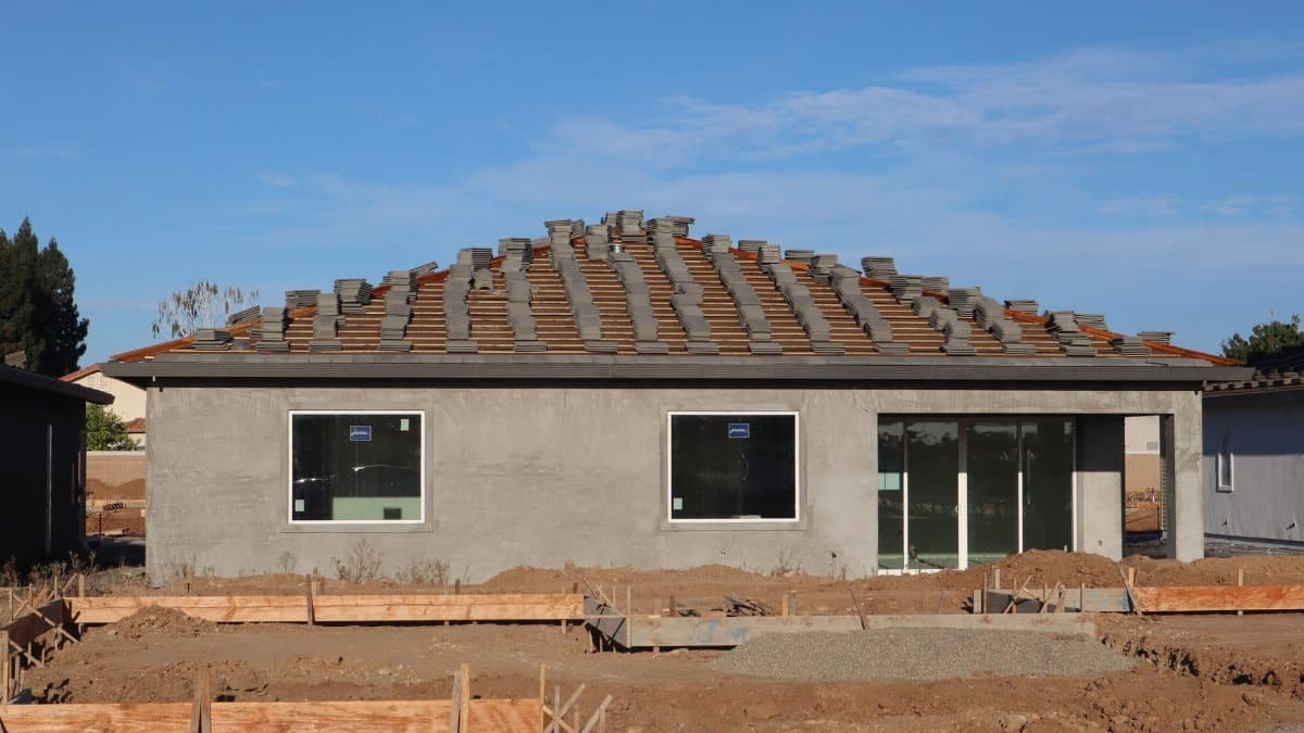 A new home under construction featuring a tiled roof and unfinished exterior.