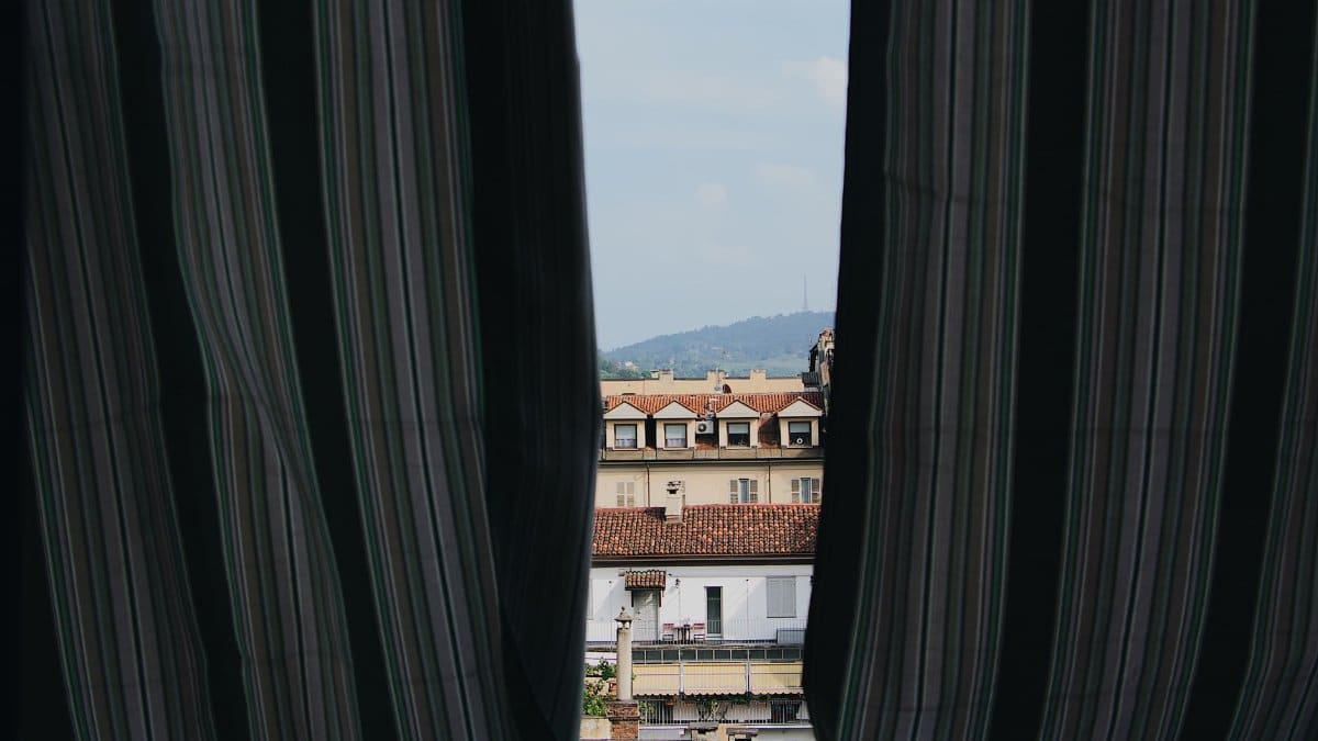 Charming cityscape view framed by striped curtains, capturing rooftops and buildings.
