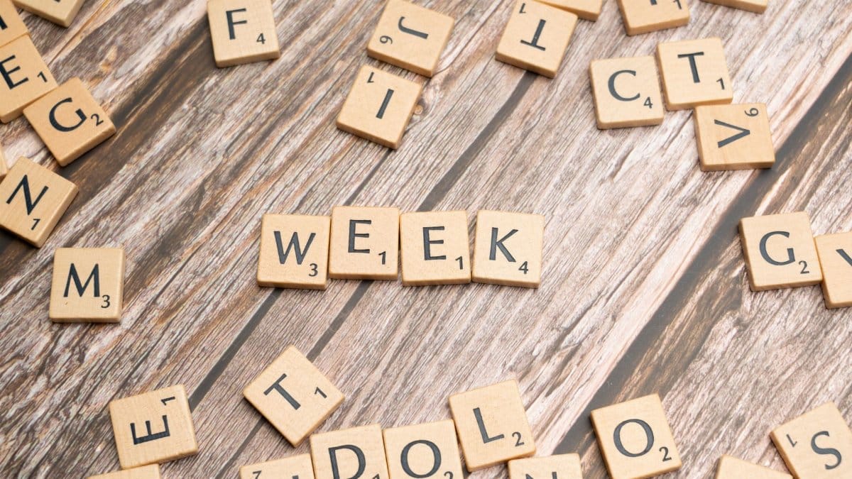 Wooden letter tiles arranged to spell 'week' on a wooden background.