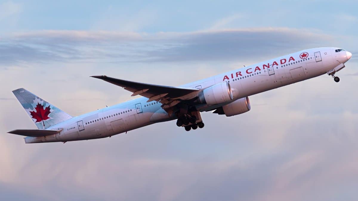 Air Canada aircraft ascending during sunset against a pink sky.