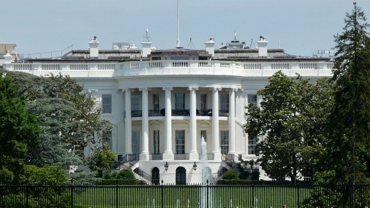 The White House in Washington DC, with tourists viewing from the lawn.