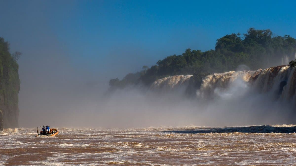 Experience thrilling rafting near stunning waterfalls surrounded by lush greenery and mist.