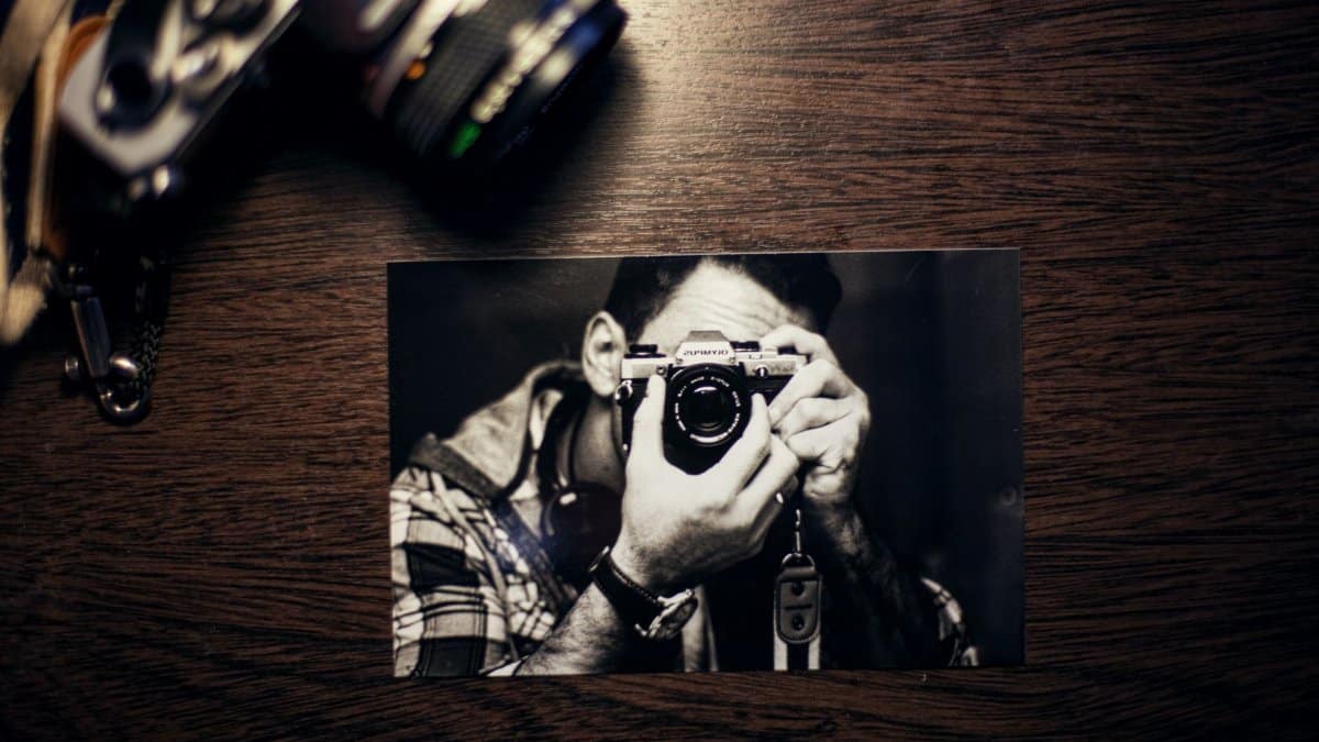 A vintage camera next to a black-and-white photograph of a person taking a picture.