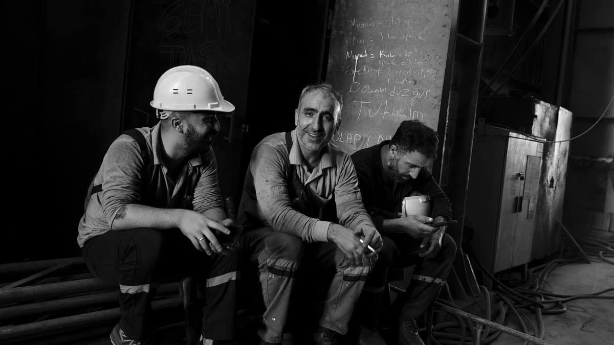 Three male workers in a factory taking a break, showcasing camaraderie and hard work.