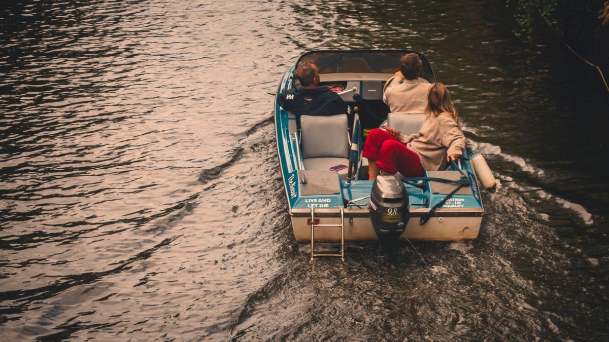 Tranquil boat ride with three people on Amsterdam canal, capturing a peaceful moment.