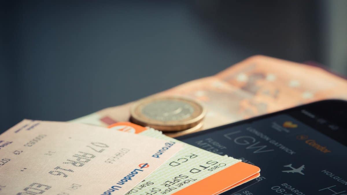 Airline ticket with euro coins and smartphone displaying flight details.